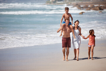 The perfect family getaway. a family walking along the beach.