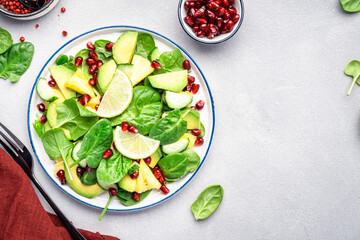 Fresh vegan salad with pineapple, arugula, avocado and dried cranberry on black stone kitchen table, top view. Healthy eating, clean diet food, weight loss concept