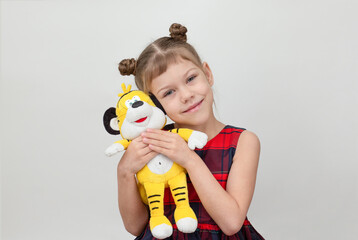 Happy and smiling child hugging tiger toy on white background caucasian little girl kid of 6 7...