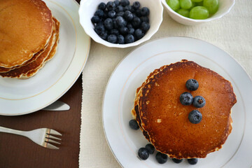 Pancake breakfast with blueberries and grapes on a set table.