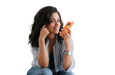 Adorable African American young woman sitting against transparent background recording audio message for boyfriend looks at camera. Attractive Brazilian girl in casual talks by phone. Communicate