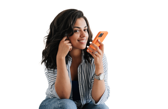 Adorable African American young woman sitting against transparent background recording audio message for boyfriend looks at camera. Attractive Brazilian girl in casual talks by phone. Communicate