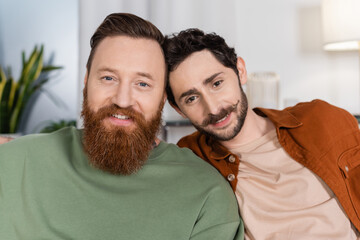 Portrait of smiling same sex couple looking at camera at home.