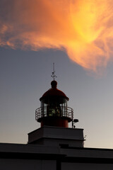 Ocean lighthouse during the sunset. Dramatic clouds on the background.