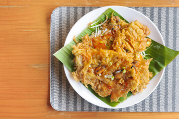 Crispy fried mussels with eggs, Thai food, served with beansprouts on banana leaf in white plate