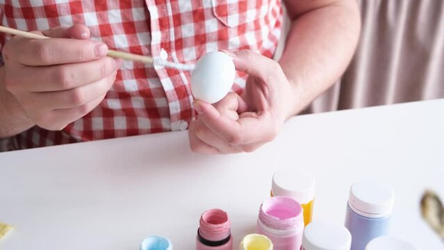Man painting easter eggs for holiday, hello spring concept, easter preparation concept. Male hands coloring eggs for Easter family holiday