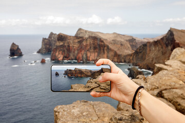 Taking photos of the cliff coastline. Using mobile phone in travel.