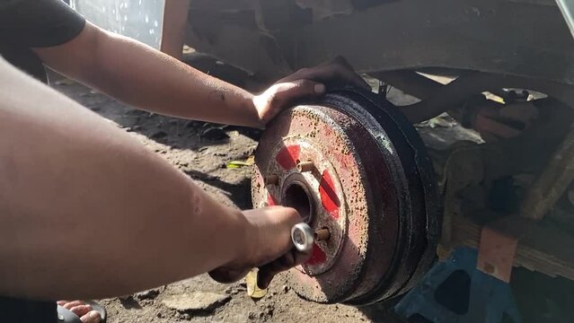 Car mechanic removing wheel axle from chassis. close up