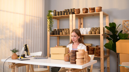 A young pretty woman entrepreneur checking and packaging craft products selling to customers in her shop