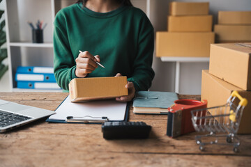 Small business entrepreneur SME owner write customer address on packaging box preparing for delivery.