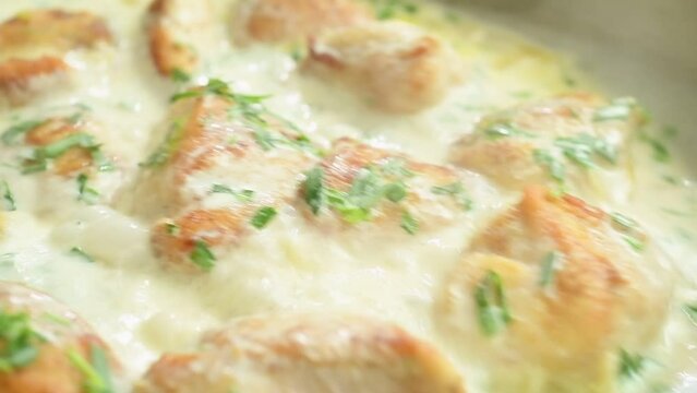 Cooking and stirring creamy tarragon chicken in the frying pan.
