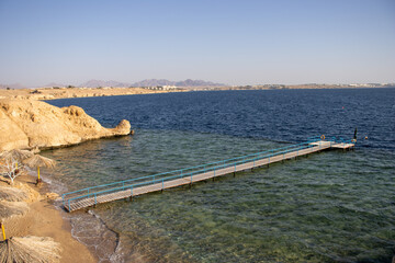 Egypt coastline with dark blue sea, clear sky and jetty