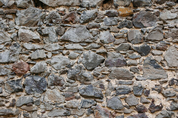Stone old wall from huge blocks. Background of stones. The concept of reliability. The space between the stones is filled with cement.