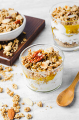 Granola and Yogurt Parfaits, Healthy Breakfast or Snack, Muesli with Nut Mix and Honey on Bright Concrete Background