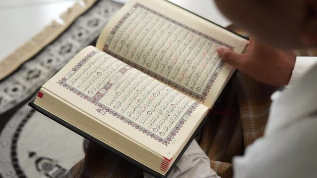 man opens the pages of holy Quran