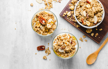 Granola and Yogurt Parfaits, Healthy Breakfast or Snack, Muesli with Nut Mix and Honey on Bright Concrete Background