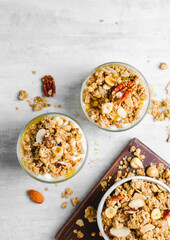 Granola and Yogurt Parfaits, Healthy Breakfast or Snack, Muesli with Nut Mix and Honey on Bright Concrete Background