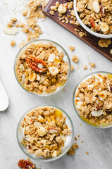 Granola and Yogurt Parfaits, Healthy Breakfast or Snack, Muesli with Nut Mix and Honey on Bright Concrete Background