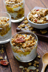 Granola and Yogurt Parfaits, Healthy Breakfast or Snack, Muesli with Nut Mix and Honey on Wooden Background