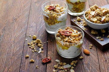 Granola and Yogurt Parfaits, Healthy Breakfast or Snack, Muesli with Nut Mix and Honey on Wooden Background