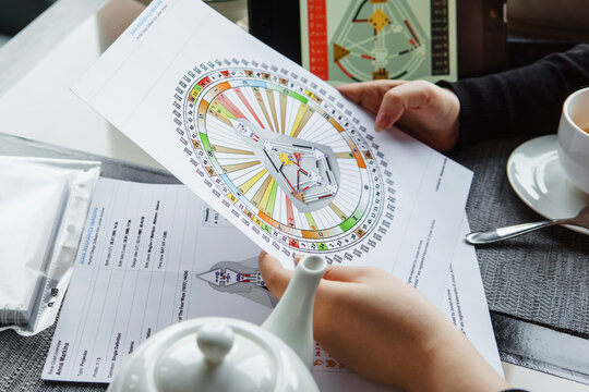 TVER, RUSSIA - FEBRUARY 12, 2023: A woman at the table is studying a rave mandala by human design. Rave mandala on the table close-up. The concept of esoteric teachings.