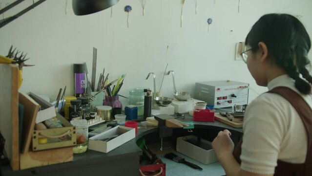The girl works in her atmospheric craft workshop with jewellery.