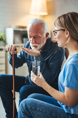 Medicine And Health Care Concept. Smiling young doctor showing elderly male patient pills, pointing at tablets. Female specialist prescribing mature man treatment, painkiller or vitamin