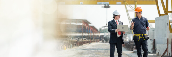 Web banner Male engineers inspecting and controlling the work of the employees and  quality of the manufactured products to meet standards In industrial factories producing precast prefabricated wall