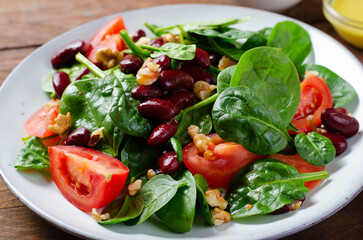 Red Bean Salad On Wooden Background, Fresh Salad with Spinach, Cherry Tomatoes, Walnuts, Beans and Mustard Dressing