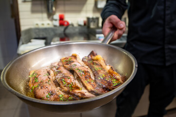 man chef cooking fried meat slice in frying pan on restaurant kitchen