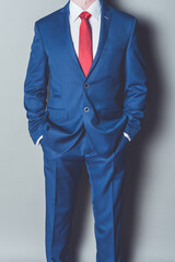 Portrait of successful businessman wearing blue siut and red tie against gray background - 578381985