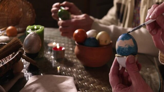Close-up of male hands painting an egg green for Easter. Focus on the object behind
