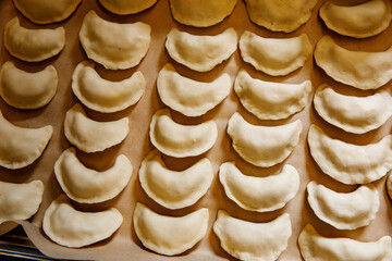 Raw homemade dumplings on a tray.