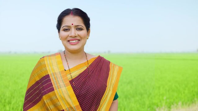 Happy Confident village woman standing by looking at camera at agriculture farm land - concept of empowerment, inspirational and successful agribusiness.