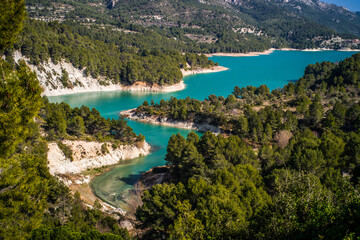 Fototapeta na wymiar Lake Guadalest, rocky mountains and hills covered with trees. Blue sky