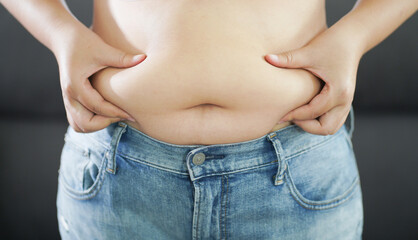 Naklejka premium Obese Woman with fat upset about her belly. Overweight woman touching his fat belly and want to lose weight. Fat woman with tight clothing worried about weight diet lifestyle concept