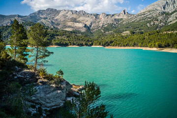Fototapeta na wymiar Lake Guadalest, rocky mountains and hills covered with trees. Blue sky
