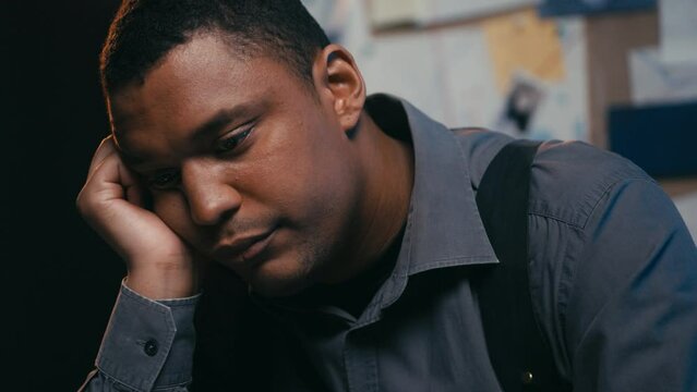 Bored police detective looking at laptop screen, falling asleep while on duty