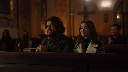 Husband and wife attentively listen to the preaching of the priest. A married couple sitting in a Catholic church smiling during a sermon.