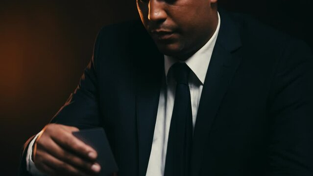 Serious businessman checking poker card, bluffing to win, high stakes on table
