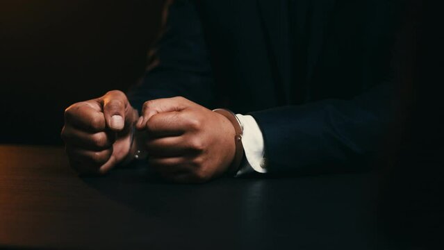 Close-up hands of man in business suit in handcuffs, fraud suspect making fists