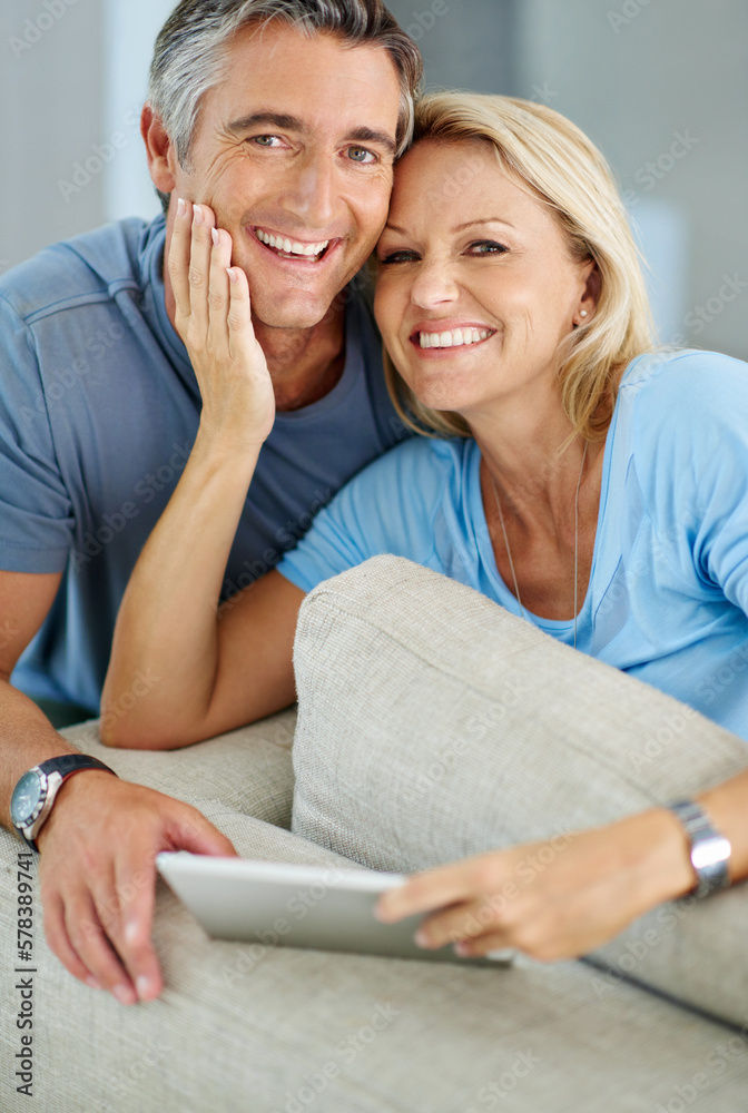 Poster We always make the most of our time together. Portrait of a smiling couple sitting at home using a digital tablet.