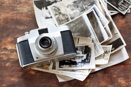 Memories to be treasured. An old-fashioned camera lying on top of a pile of black and white photographs.
