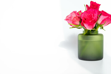 Pink roses in a green vase on a white background