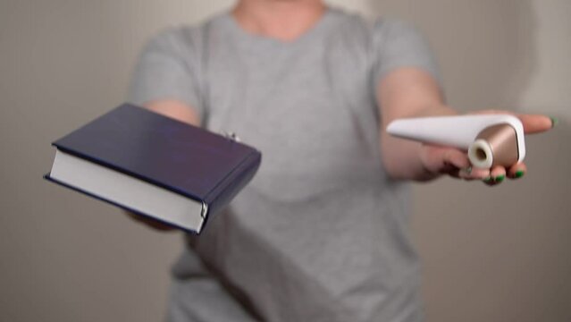 a woman in a gray t-shirt holds an adult sex toy and a book in her hands. slow motion video. close up. High quality Full HD video recording