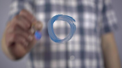 A young man draws a symbol of diabetes on the glass. A man draws a blue circle on the glass with a brush.