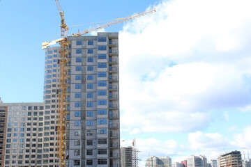 Fototapeta premium construction of apartament against the blue sky. construction site with crane. big building in the city