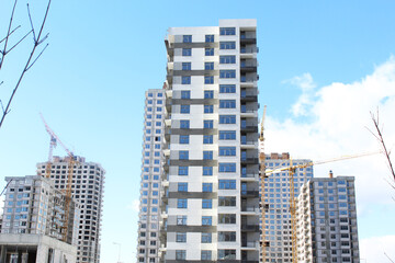 Fototapeta na wymiar construction of apartament against the blue sky. construction site with crane. big building in the city