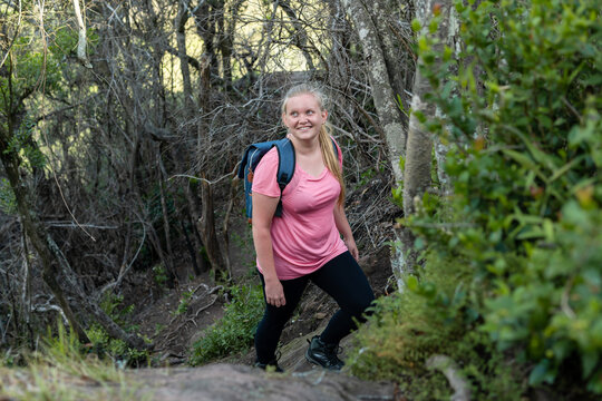 happy female hiker walking in the woods with backpack in forest trail