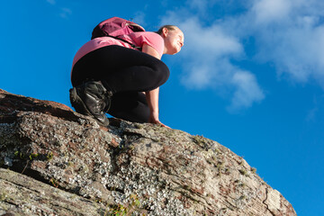 adventurous female hiker looking at view on top of rock in the forest